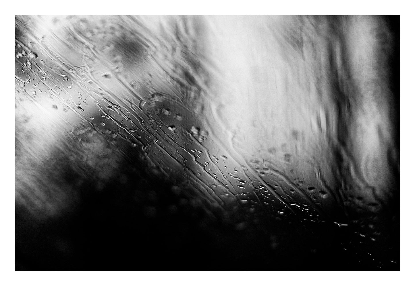 Coastal Noir 7933 - 104x74cm, abstract black and white coastal image with fine rain droplets on glass creating subtle horizontal lines and textures.