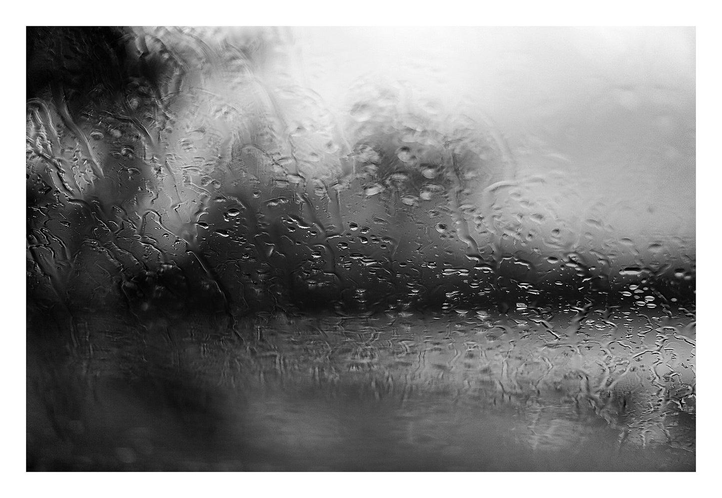 Coastal Noir 7974 - 104x74cm, black and white coastal photograph with rain-speckled glass creating soft abstract forms and horizontal flow.