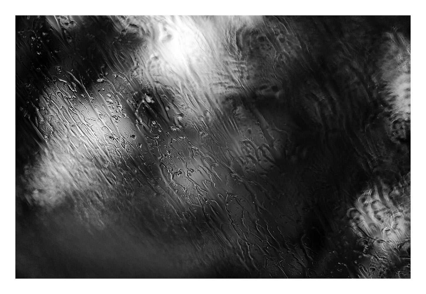 Coastal Noir 7982 - 104x74cm, abstract black and white coastal image with layered rain textures over blurred trees and shoreline.