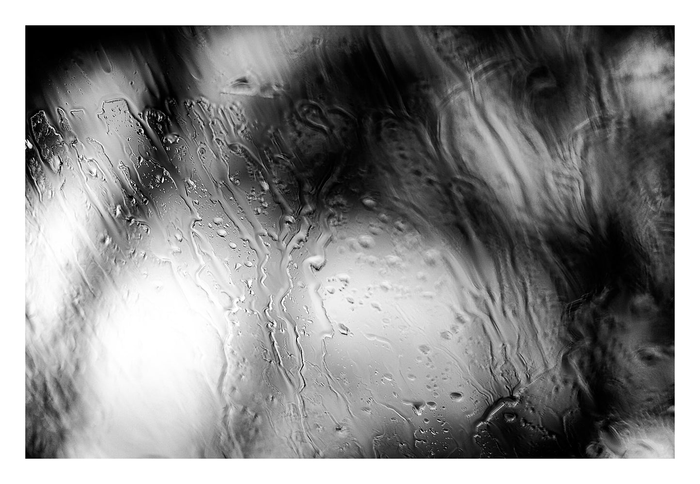 Coastal Noir 8000 - 104x74cm, black and white minimalist coastal photograph of rain-dappled glass with soft focus trees behind.