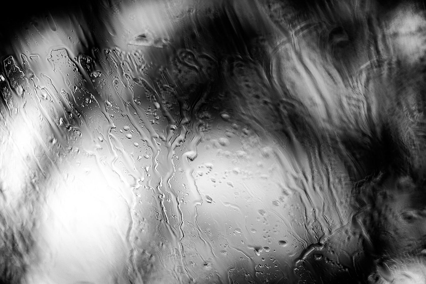 Coastal Noir 8000 - 90x60cm, black and white minimalist coastal photograph of rain-dappled glass with soft focus trees behind.