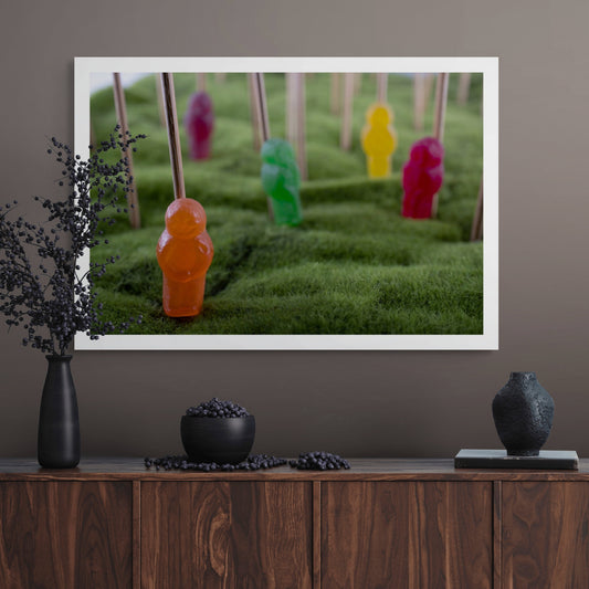 Babes in the Woods 2613v1 - Room View, whimsical fine art photograph featuring colourful jelly baby figures on green textured terrain, skewered on sticks, evoking themes of innocence, absurdity, and surreal displacement. Limited edition print by Raymond Mather, ART1.