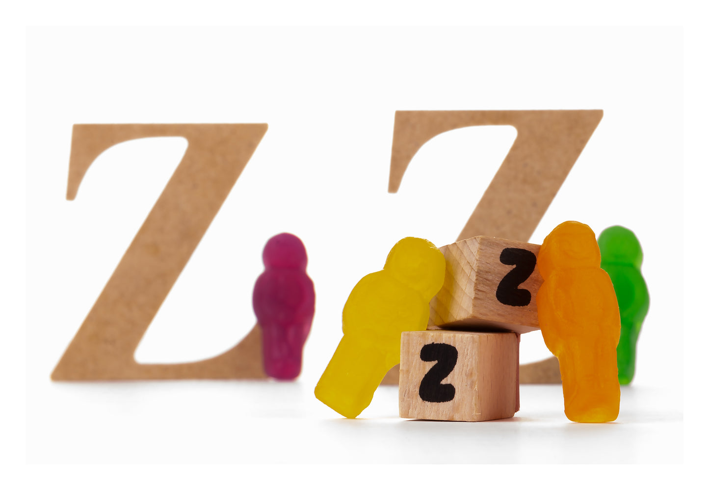 Catching Some ZZZ's 1493v3 - 104x74cm, playful fine art photograph featuring multicoloured jelly figures resting against wooden blocks marked with the letter Z, backed by large cardboard Zs, limited edition by Raymond Mather, ART1.