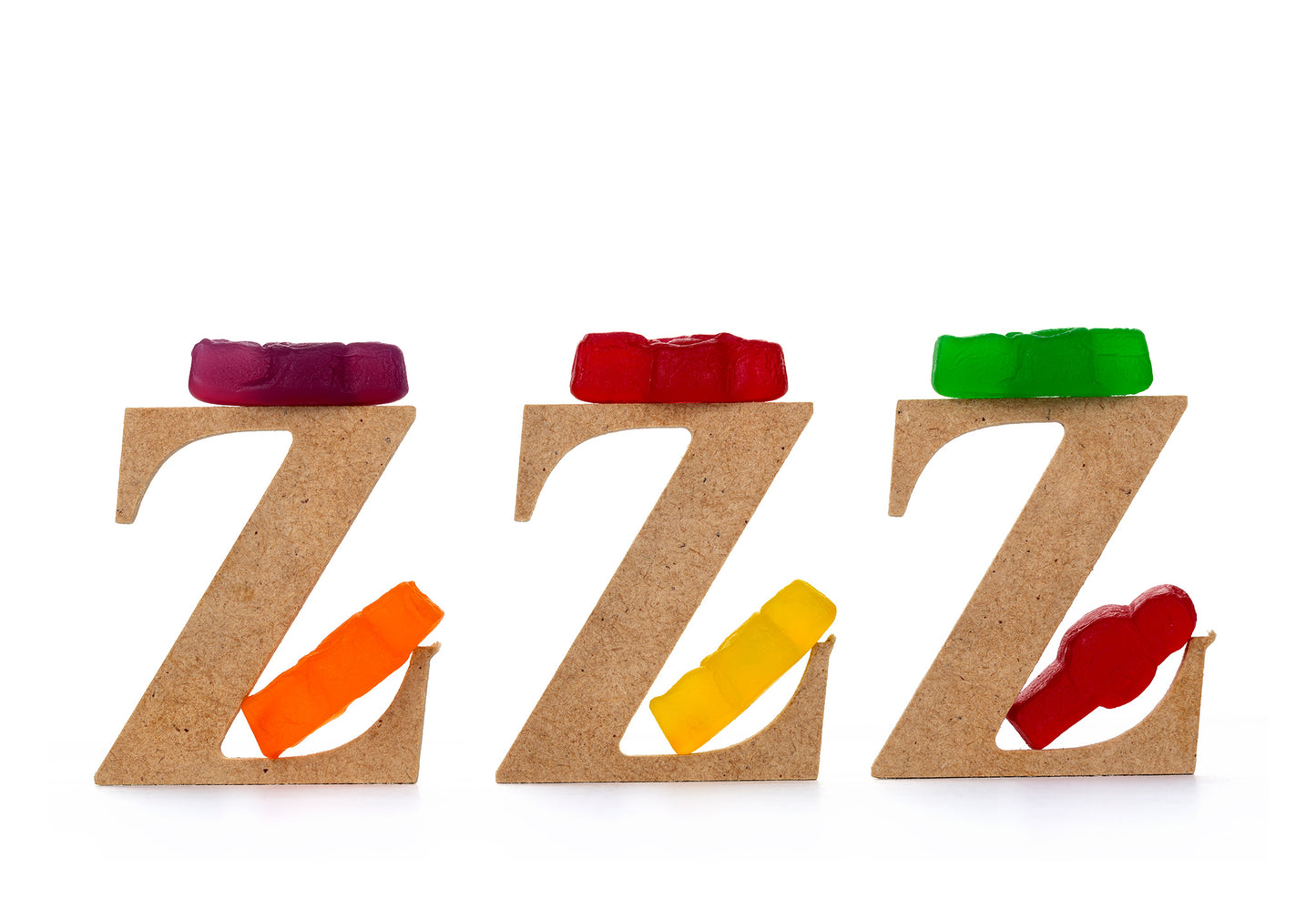 Catching Some ZZZ’s 1501 - 104x74cm, playful fine art photograph featuring three wooden letter Zs each topped with gummy bears and supported by colourful jelly baby figures, part of the Cliché Life series by Raymond Mather, ART1.
