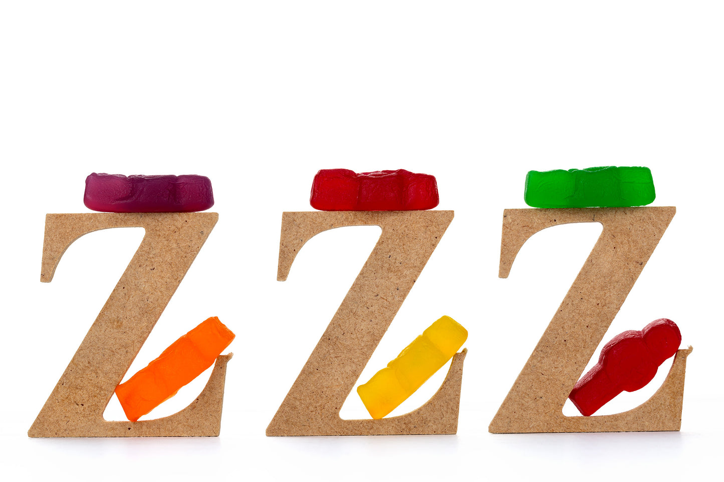 Catching Some ZZZ’s 1501 - 90x60cm, playful fine art photograph featuring three wooden letter Zs each topped with gummy bears and supported by colourful jelly baby figures, part of the Cliché Life series by Raymond Mather, ART1.