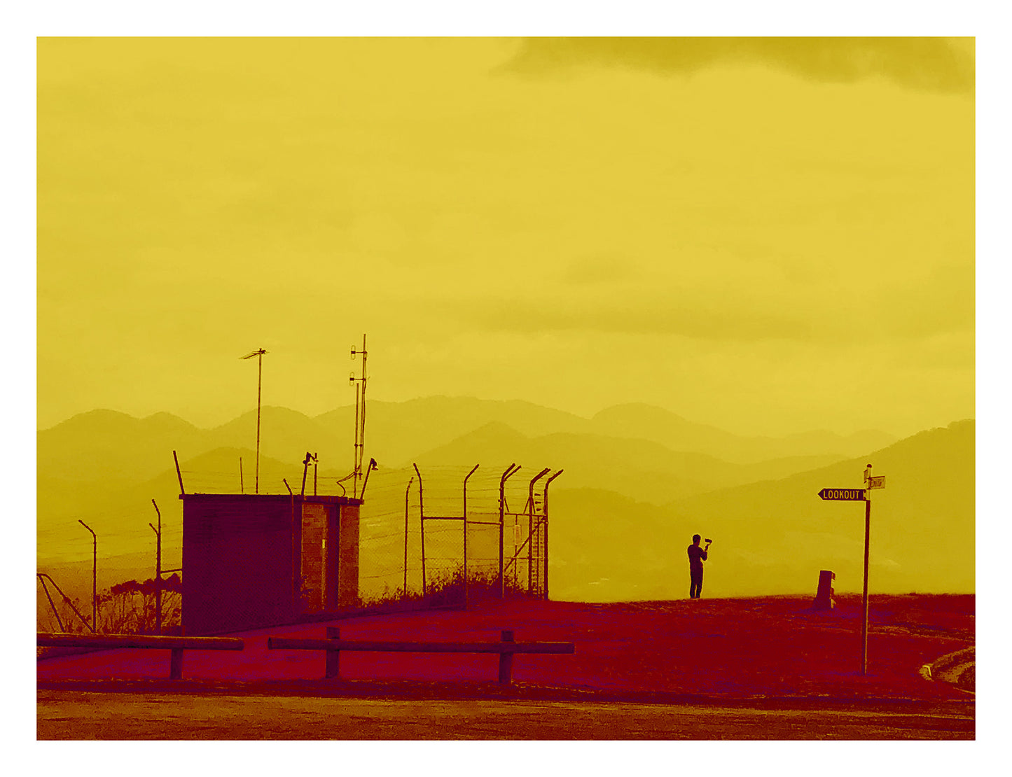 Vivid Country - Coffs Harbour The Selfie 1932v36a - 104x81.5cm, a lone figure takes a selfie at a mountaintop lookout, silhouetted against layered hills and framed by golden tones and utilitarian structures in this modern landscape portrait.