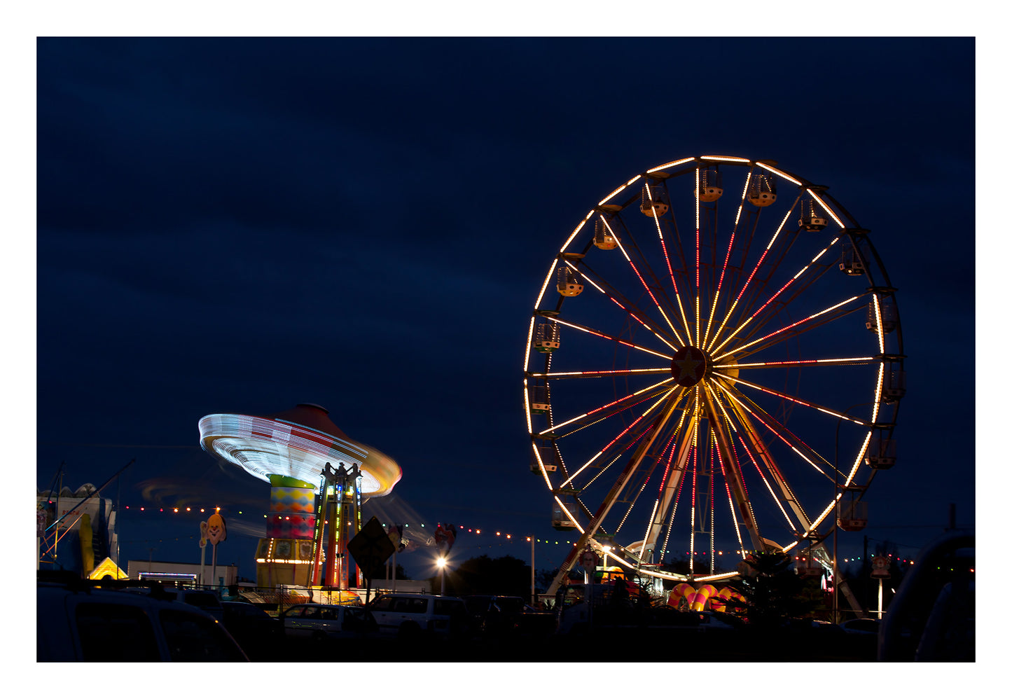 Fairground Carnival Lights 6900003v3 - 104x74cm, Ferris wheel glowing against twilight sky with carnival rides below, fine art limited edition print by Raymond Mather, ART1.