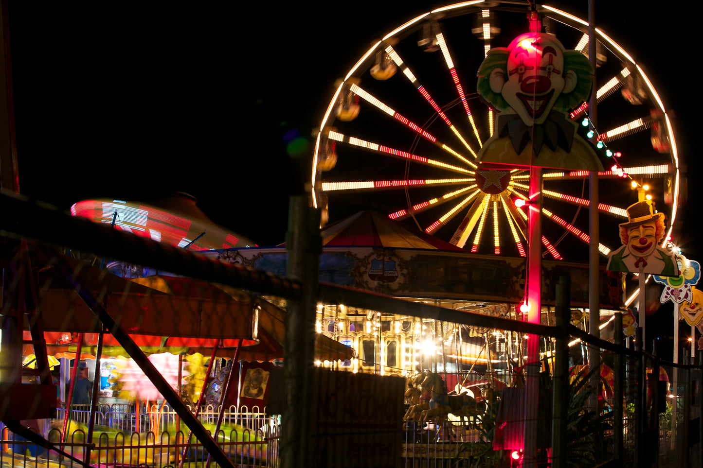 Fairground Carnival Lights 6900083 - 90x60cm, night carnival view with Ferris wheel, glowing rides, and striking clown figure, fine art limited edition print by Raymond Mather, ART1.
