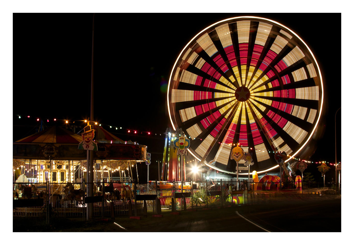 Fairground Carnival Lights 6900116 - 104x74cm, Ferris wheel with bold red and yellow pattern and carnival lights at night, fine art limited edition print by Raymond Mather, ART1.