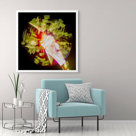 Fairground Carnival Lights 6900132 - Room View, a long exposure photograph of a spinning carnival ride, captured in a dazzling explosion of yellow, red, and white lights radiating from a central axis against a deep black sky. The blurred movement forms abstract, circular patterns, creating a vibrant and kinetic visual effect.