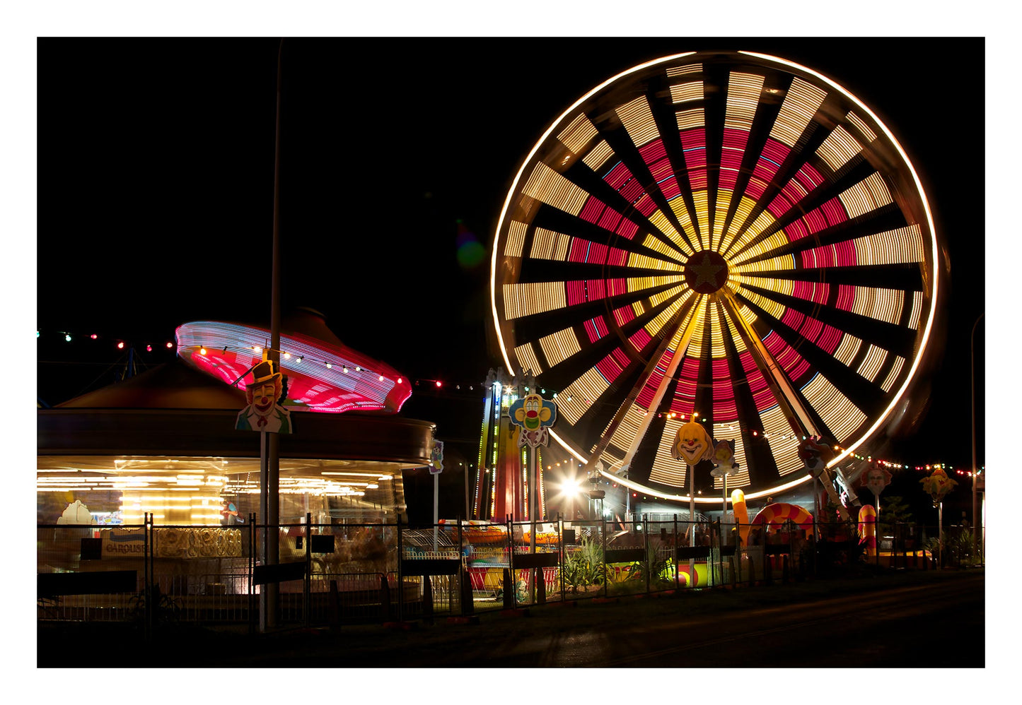 Fairground Carnival Lights 6900102 - 104x74cm, illuminated Ferris wheel and carnival rides at night with vivid red and yellow lights, fine art limited edition print by Raymond Mather, ART1.