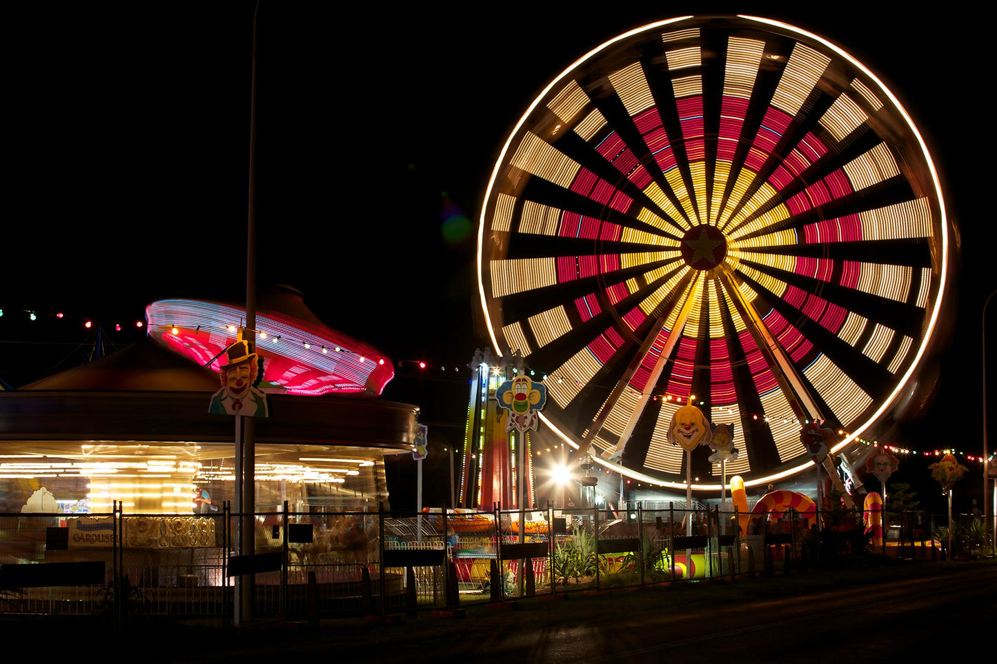 Fairground Carnival Lights 6900102 - 90x60cm, illuminated Ferris wheel and carnival rides at night with vivid red and yellow lights, fine art limited edition print by Raymond Mather, ART1.
