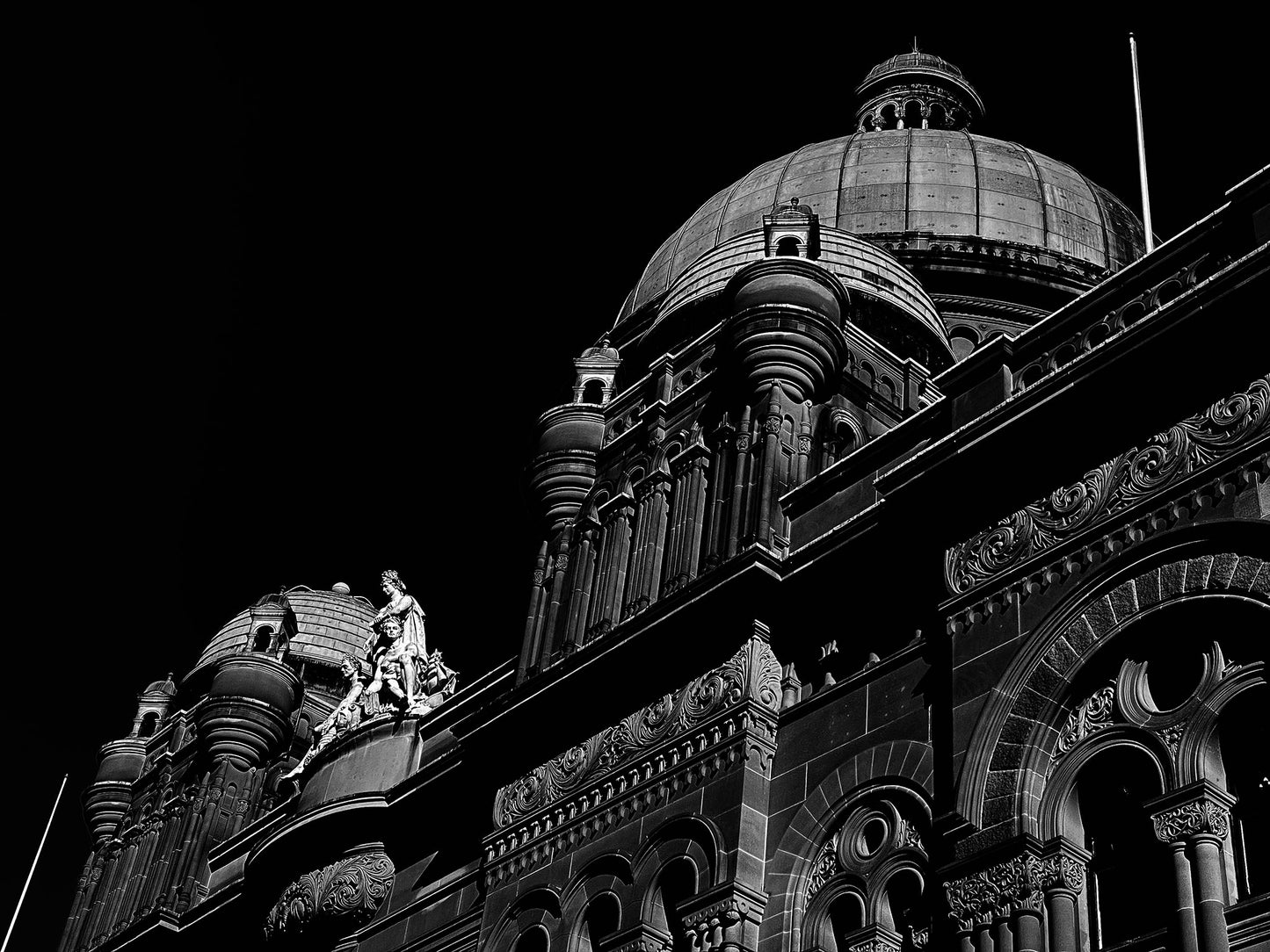 Monochrome Mix - Sydney - QVB - 231101v3 - 90x67.5cm, Black and white photograph of the Queen Victoria Building in Sydney, featuring ornate domes, detailed façade architecture, and classical sculpture against a dark sky.