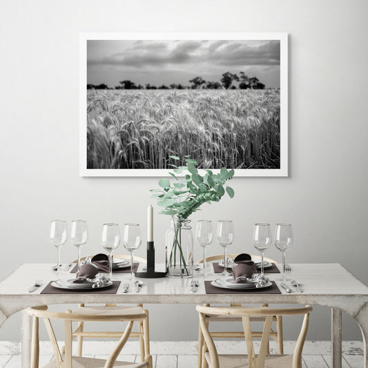 Monochrome Mix - Wheat Field - 258559v1 - Room View, A black and white photograph of a ripening wheat field under a cloudy sky, with trees in soft focus on the horizon. Textured, atmospheric rural landscape. Limited edition fine art print.