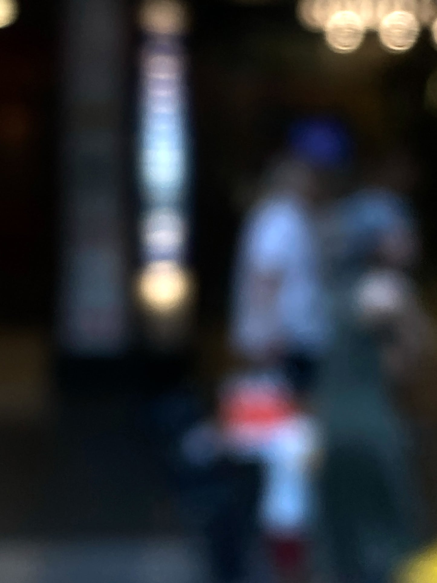 Urban Commute - Series No.1: 0974v1 - 67.5x90cm, a soft-focus photograph of two blurred adult figures with a small child in red and white, framed by glowing city lights and vertical signage. A quiet moment of connection and motion captured in painterly abstraction. Limited edition fine art print by Raymond Mather.