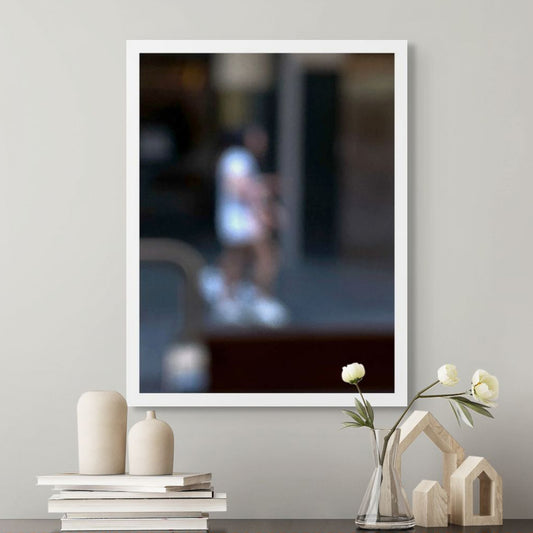 Urban Commute - Series No.1: 0979v1 - Room View, a soft focus photograph of two city walkers side by side, dressed in light tones with glowing white shoes, set against a deep urban backdrop. A gesture of shared movement and quiet rhythm. Limited edition fine art print by Raymond Mather.