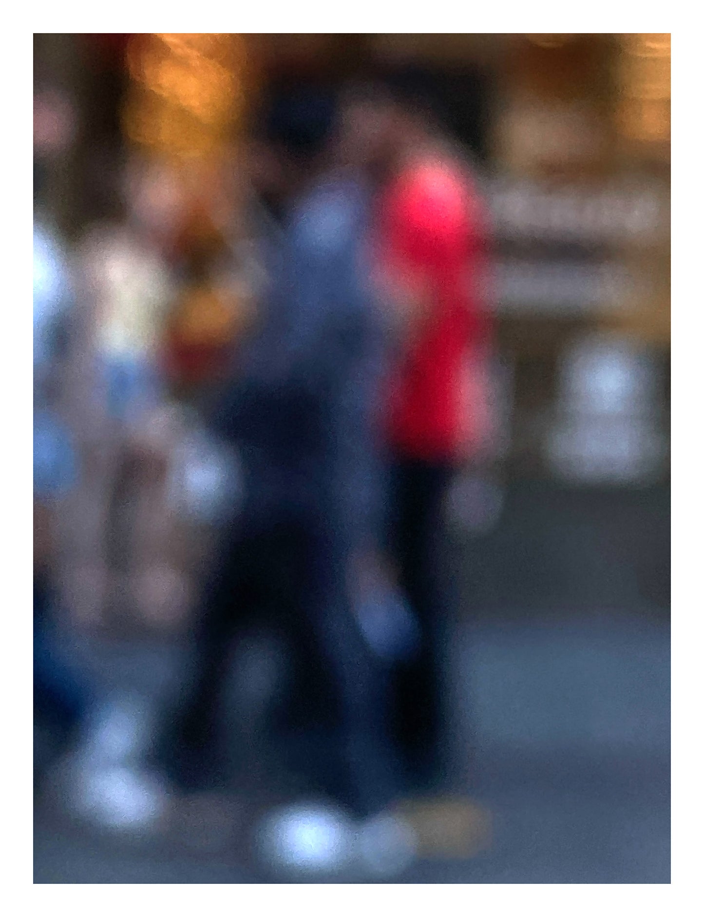 Urban Commute - Series No.1: 0983v1 - 81.5x104cm, a soft focus photograph of blurred pedestrians in motion, with one figure in bright red passing a golden-lit city storefront. A painterly exploration of rhythm, anonymity, and colour in the urban commute. Limited edition fine art print by Raymond Mather.