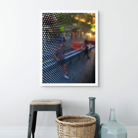 Urban Commute - Series No.2: 0785 - Room View, fine art photograph by Raymond Mather featuring a blurred pedestrian viewed through a perforated window screen. Vibrant colours of red, purple, and green shimmer across the gridded surface, creating a dynamic abstract portrait of city life in motion.