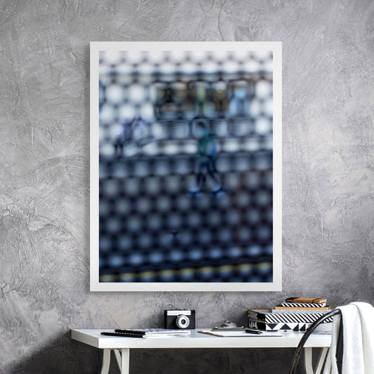 Urban Commute - Series No.2: 9150 - Room View, fine art photograph by Raymond Mather showing a walking figure in blue, captured through a dense circular grid. A blurred train forms the backdrop, creating a quiet, geometric abstraction of city life in motion.