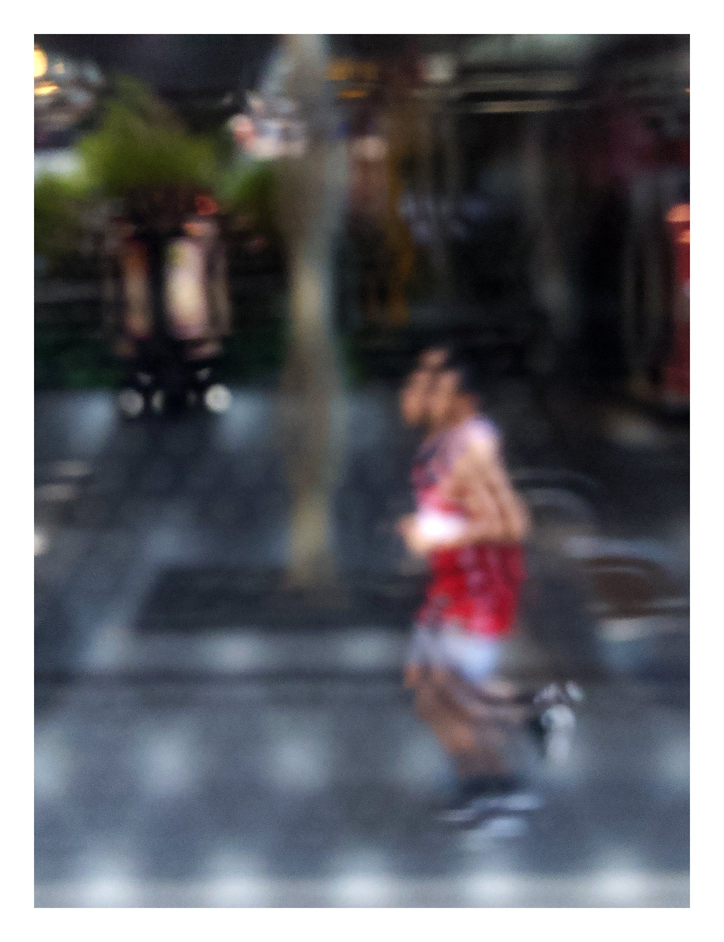 Urban Commute - Series No.2: 9199v1 - 81.5x104cm, fine art photograph by Raymond Mather featuring a blurred runner in red, captured mid-stride through a soft patterned lens. The urban backdrop is abstracted into colour and shadow, evoking a dreamlike sense of motion and energy.