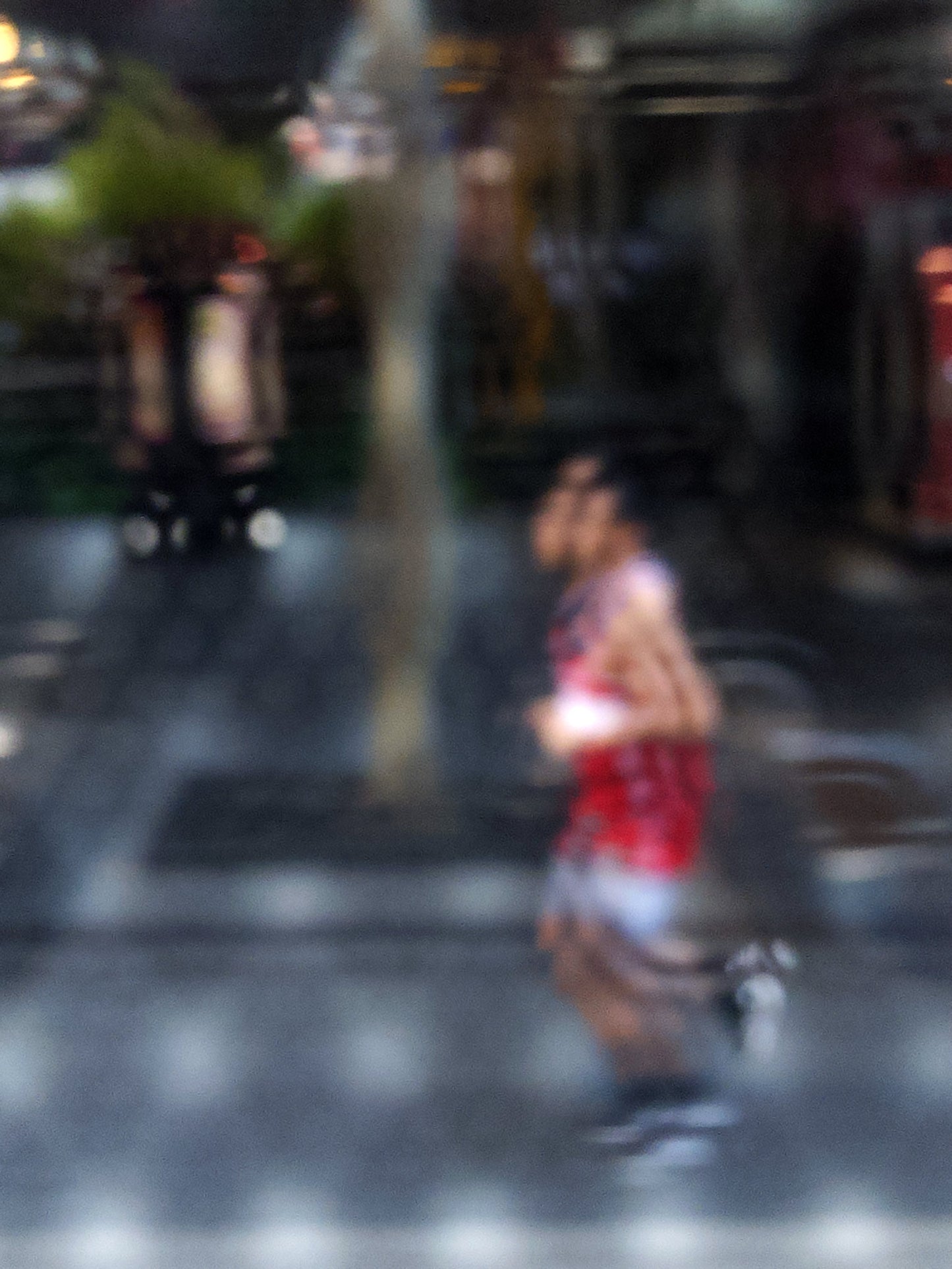 Urban Commute - Series No.2: 9199v1 - 67.5x90cm, fine art photograph by Raymond Mather featuring a blurred runner in red, captured mid-stride through a soft patterned lens. The urban backdrop is abstracted into colour and shadow, evoking a dreamlike sense of motion and energy.