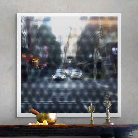 Urban Commute - Series No.2: 9201(1)v1a - Room View, fine art photograph by Raymond Mather showing blurred cars with headlights approaching an intersection, viewed through a patterned surface. City buildings rise on either side, creating a dreamlike abstract of light, rhythm, and perspective.