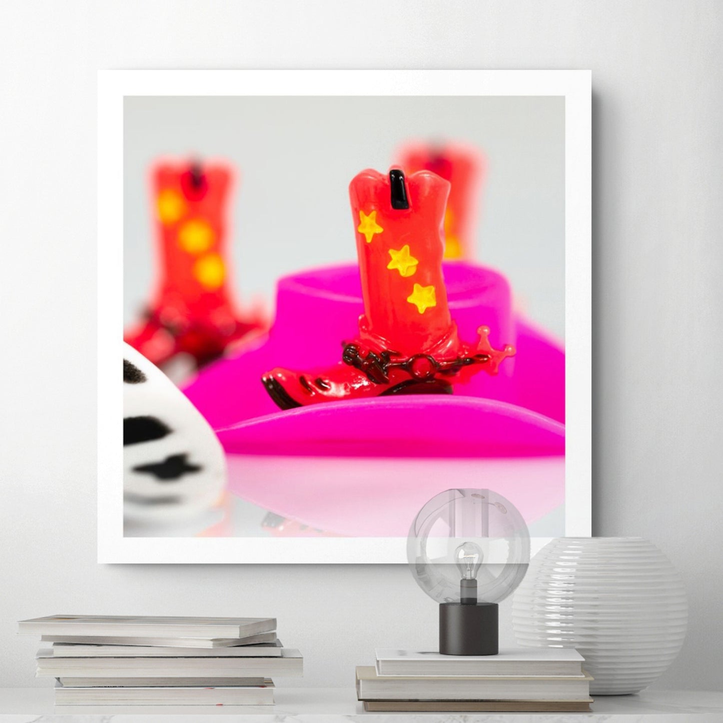 Boot Scootin’ Baby 266837v1 by Raymond Mather displayed as a square photographic artwork in a contemporary white interior above stacked books and decorative objects.