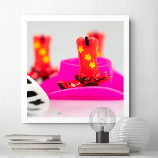 Boot Scootin’ Baby 266837v1 by Raymond Mather displayed as a square photographic artwork in a contemporary white interior above stacked books and decorative objects.