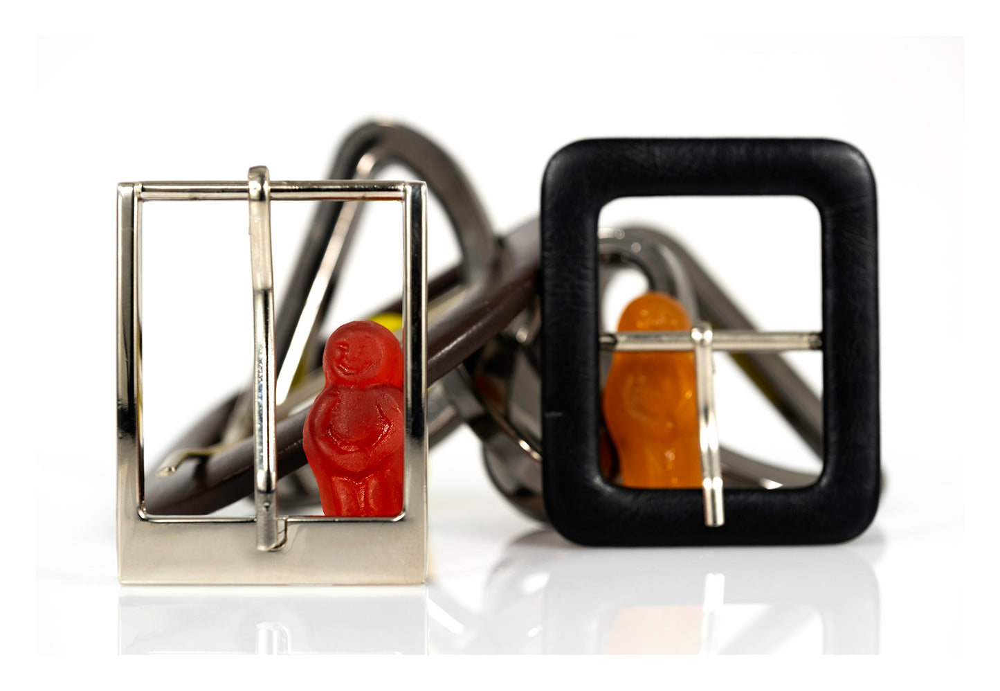 Red and orange miniature figures positioned within silver and black belt buckles against a white background.