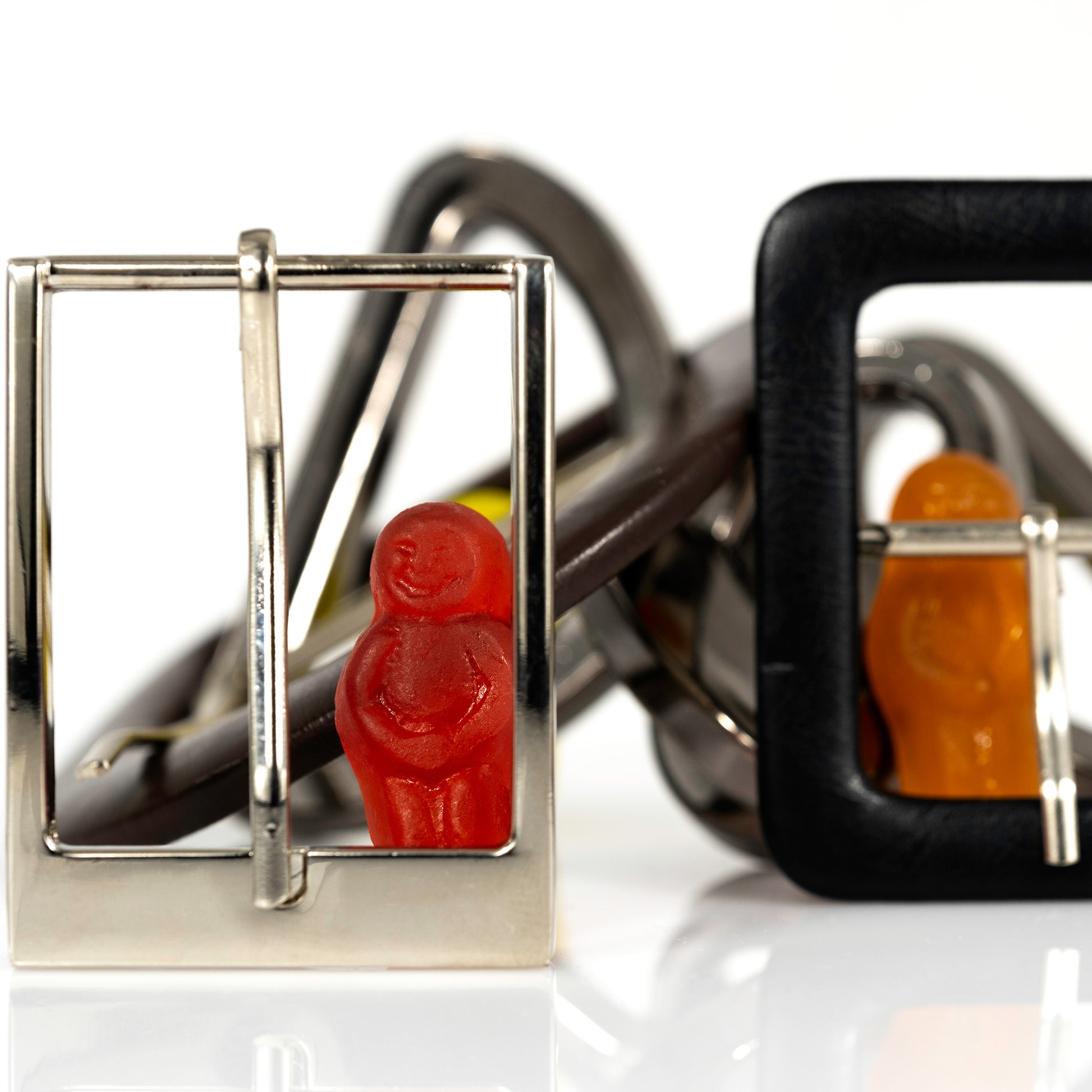 Close view of a red miniature figure framed inside a polished silver buckle with an orange figure behind a black buckle.