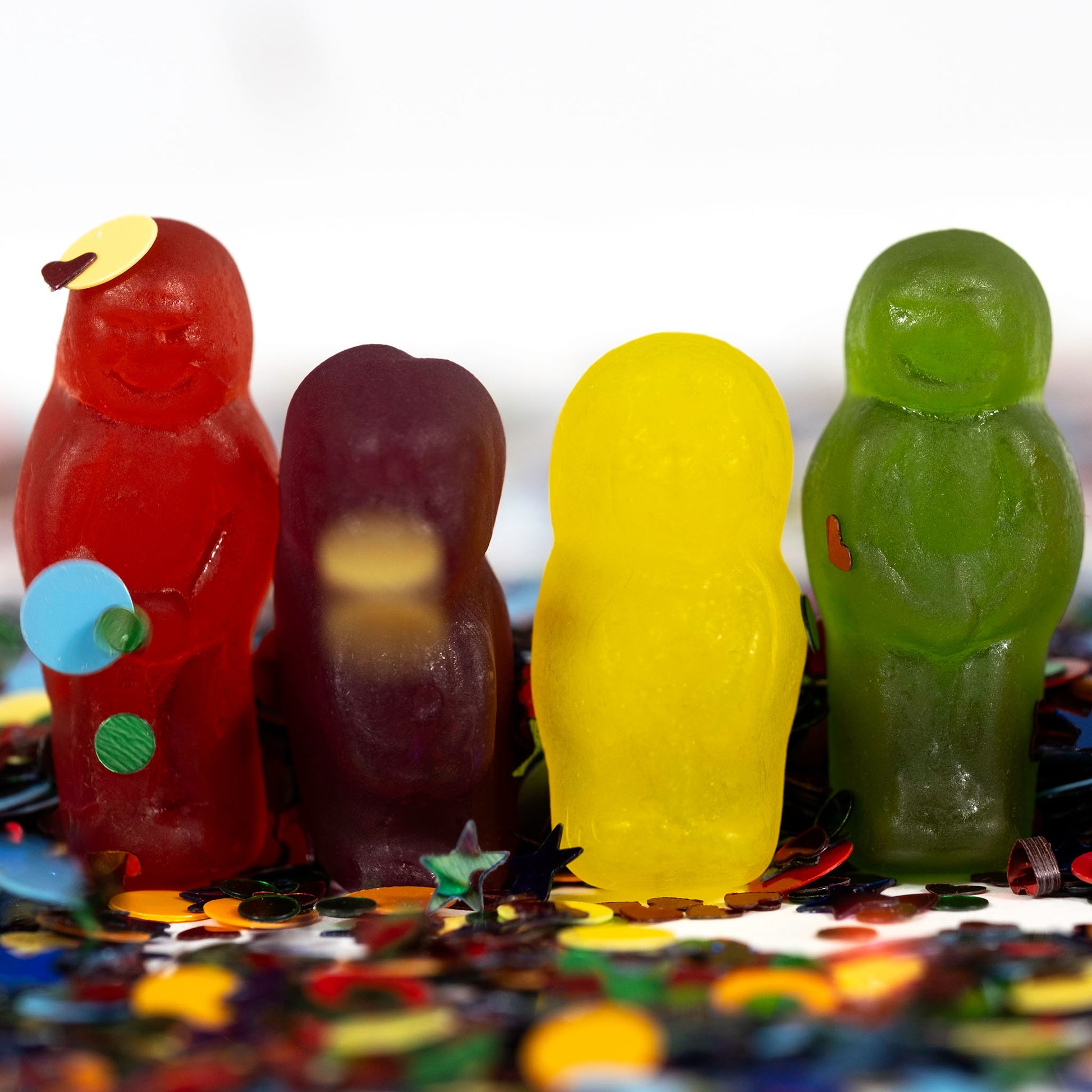 Close view of red, purple, yellow and green miniature figures standing among colourful metallic confetti.