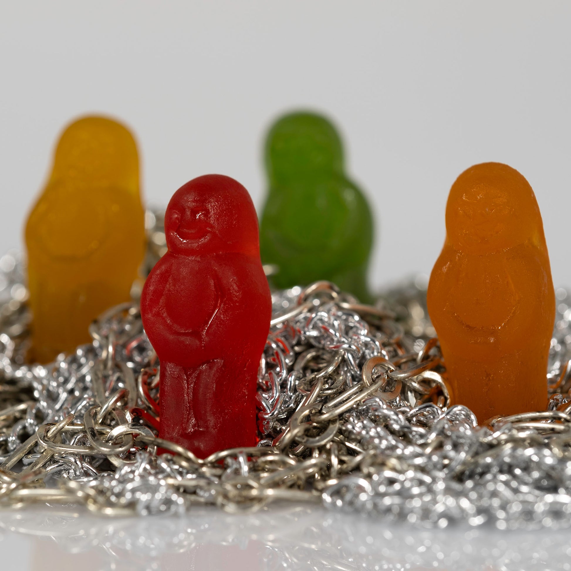 Close view of a red miniature figure surrounded by tangled metallic chains, with orange, yellow and green figures behind.