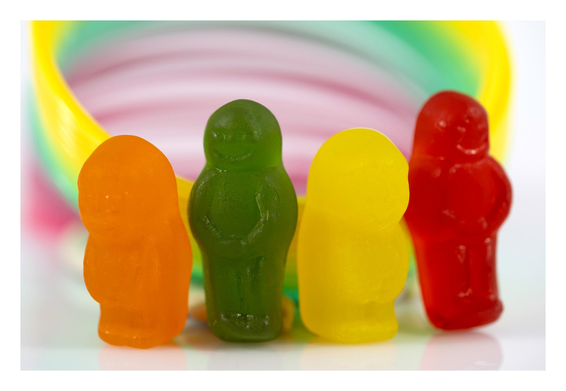 Orange, green, yellow and red miniature figures standing together in front of sweeping circular bands of pink, green and yellow.
