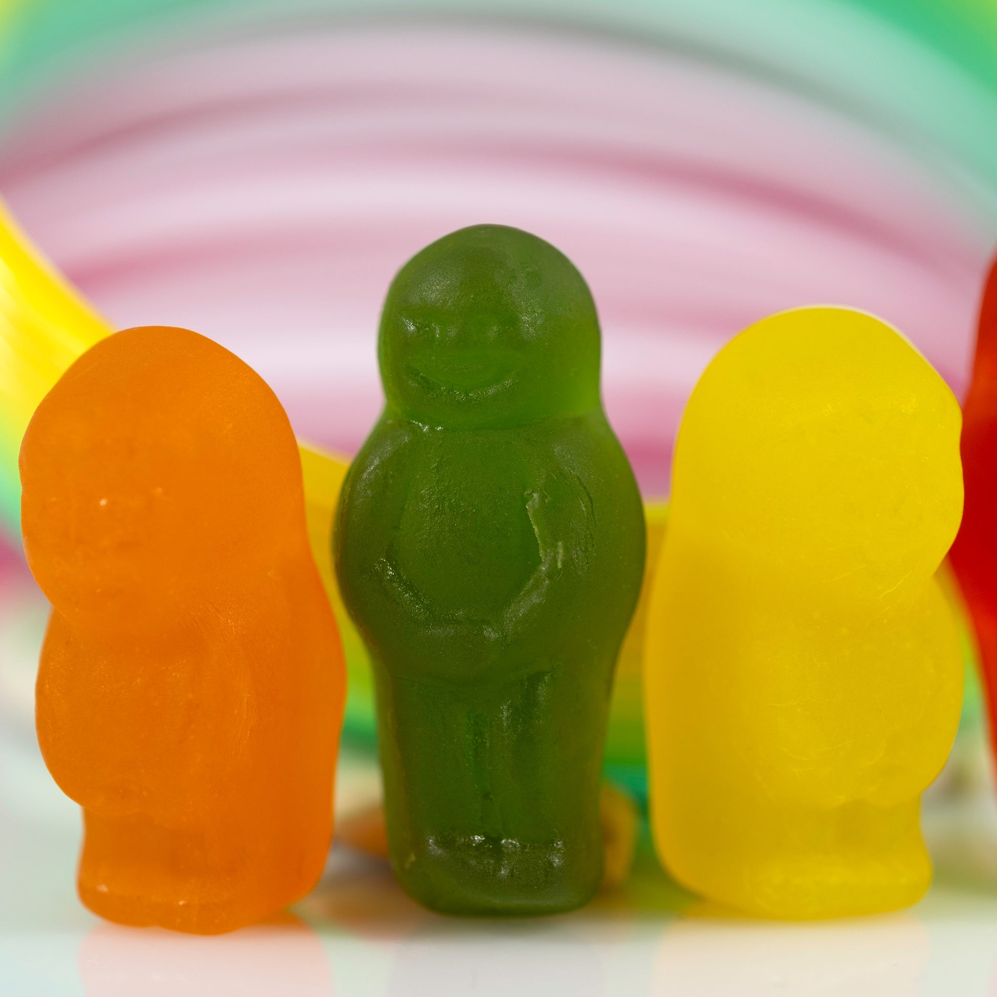 Close-up of orange, green and yellow miniature figures against softly blurred circular bands of pink, green and yellow.