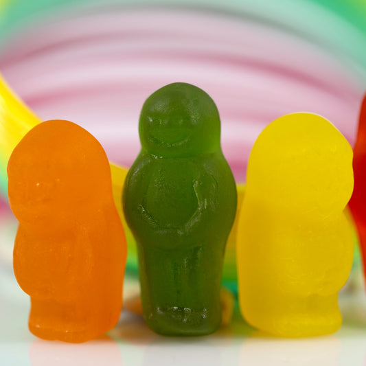 Close-up of orange, green and yellow miniature figures against softly blurred circular bands of pink, green and yellow.