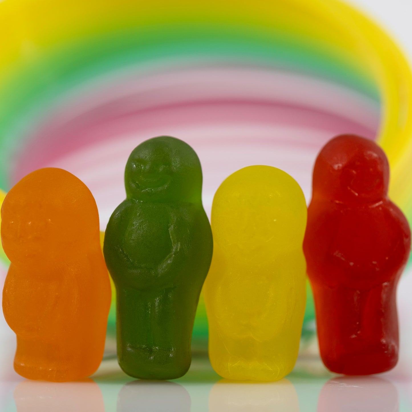 Close-up of four colourful miniature figures grouped together beneath a sweeping multicoloured circular form.