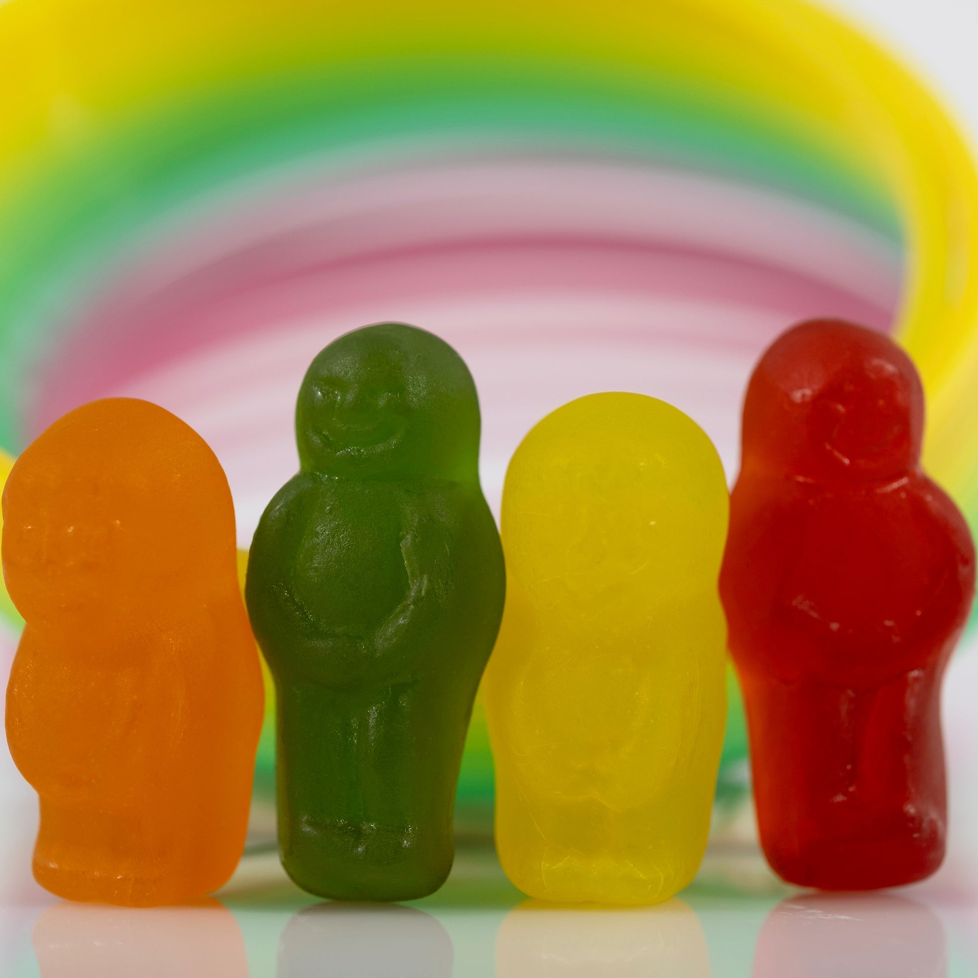 Close-up of four colourful miniature figures grouped together beneath a sweeping multicoloured circular form.