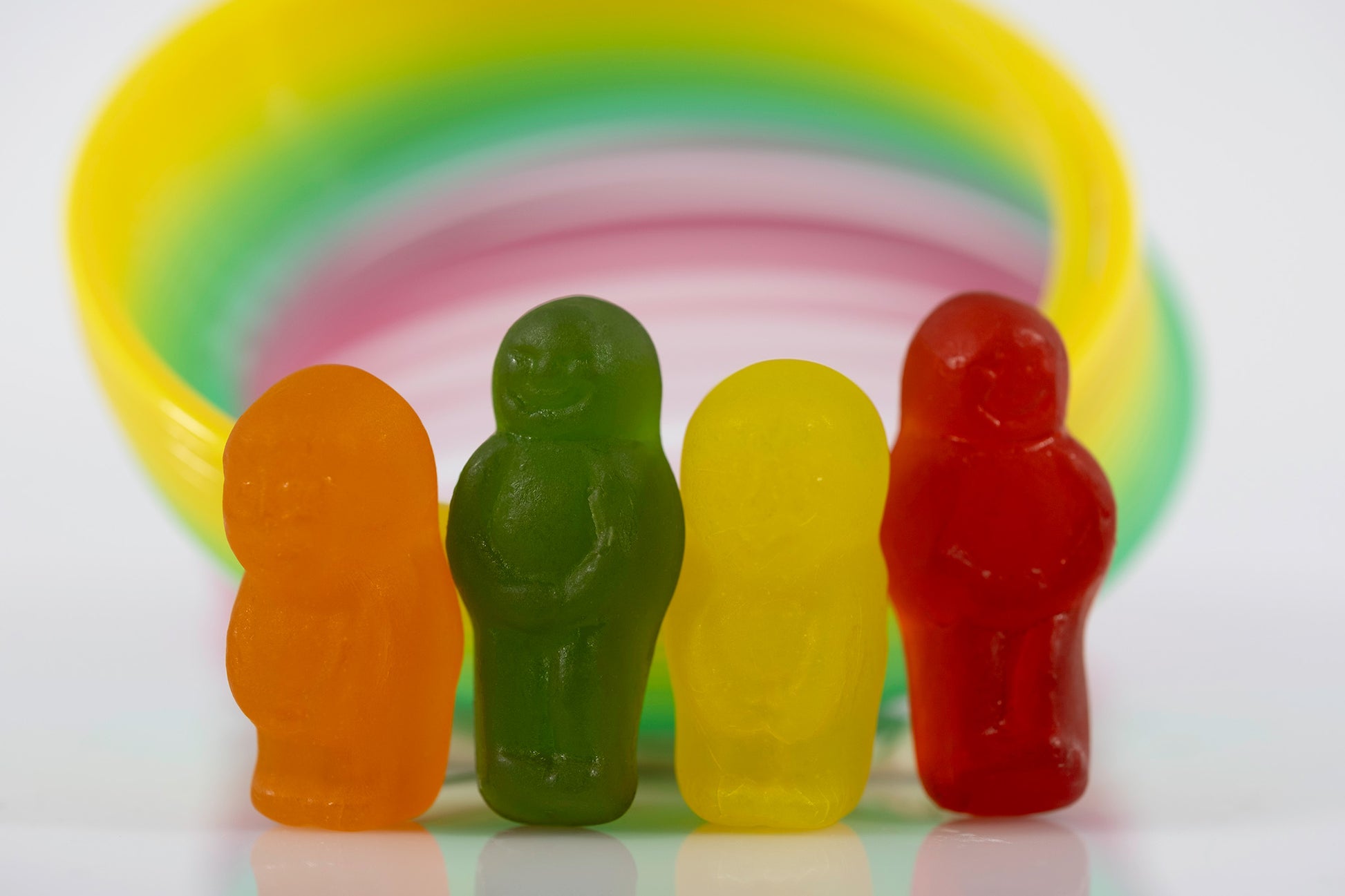 Orange, green, yellow and red miniature figures standing together against a softly focused circular background.