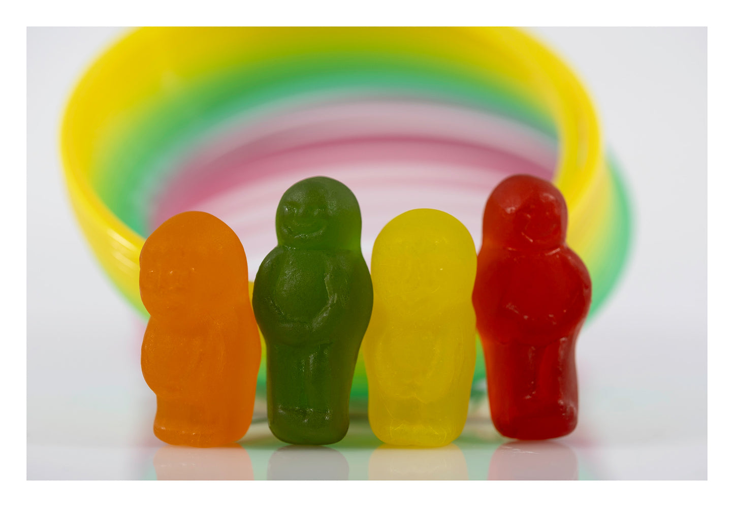 Four orange, green, yellow and red miniature figures standing beneath concentric bands of yellow, green and pink.