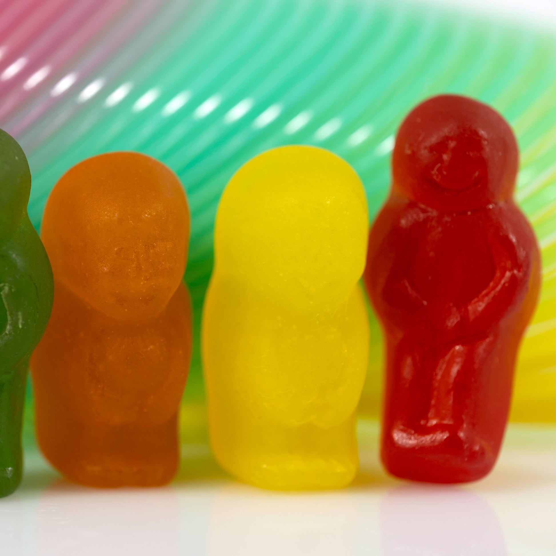 Close-up crop of colourful miniature figures against a vibrant curved background of turquoise, pink and yellow.