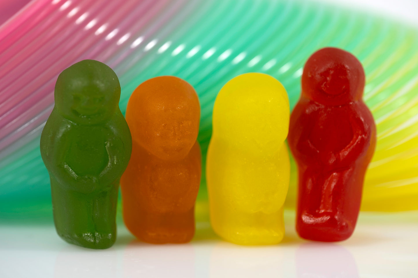 Four colourful miniature figures arranged in a row against sweeping multicoloured bands.