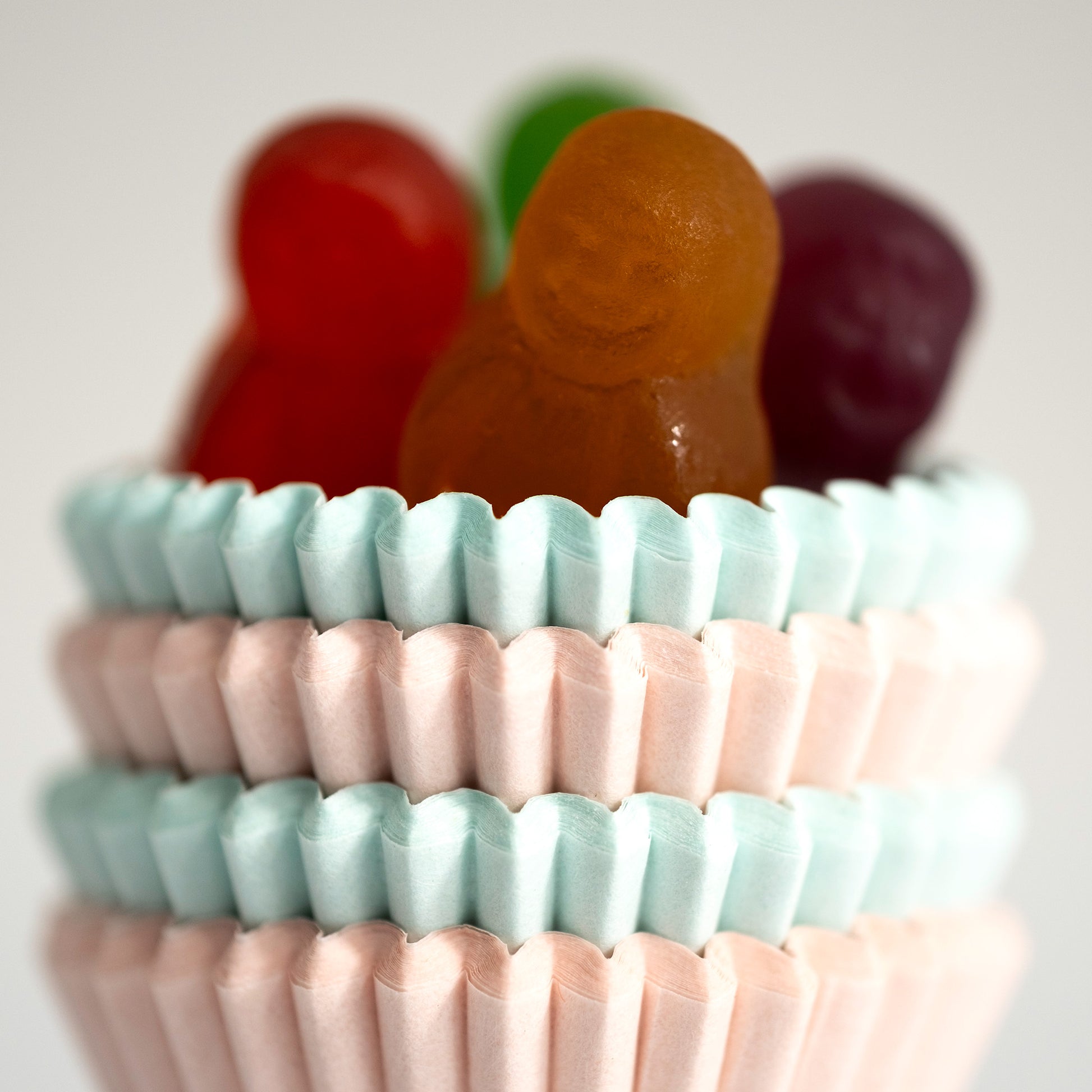 Close-up of an orange miniature figure surrounded by red, green and purple figures above stacked pastel cupcake cases.