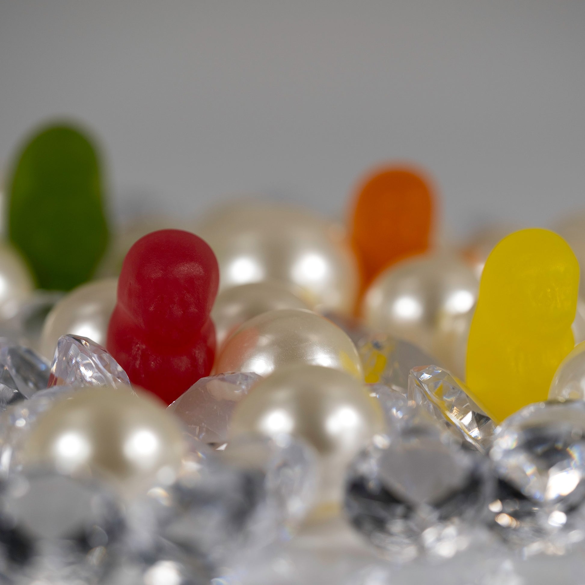 Close view of red and yellow miniature figures emerging among luminous pearls and transparent crystal-like forms.