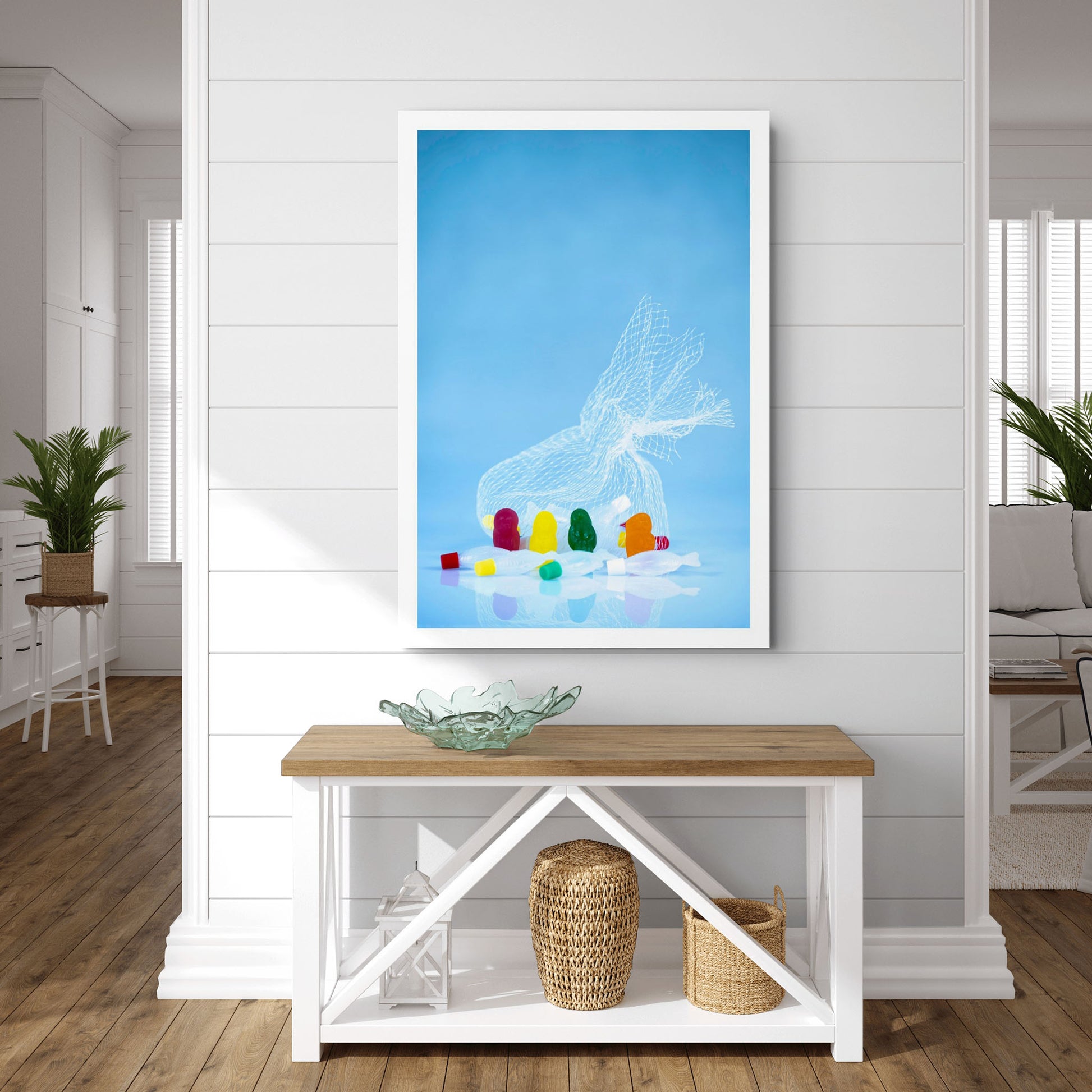 Large blue portrait photographic artwork showing colourful gummy figures, fish and a white net, displayed in a bright contemporary interior.