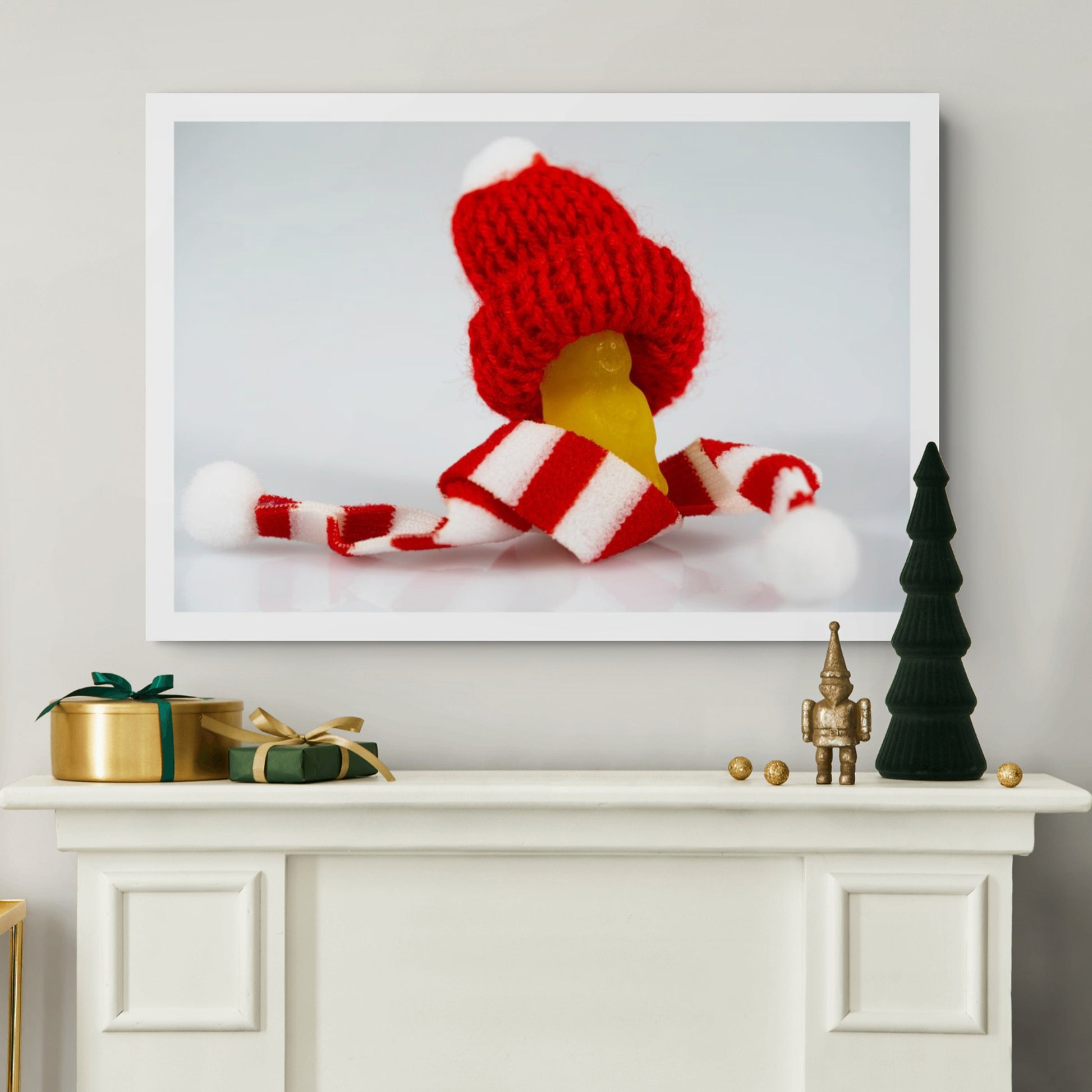 Santa Babies photographic artwork featuring a tiny yellow figure in oversized red and white Christmas clothing displayed above a decorated mantel.