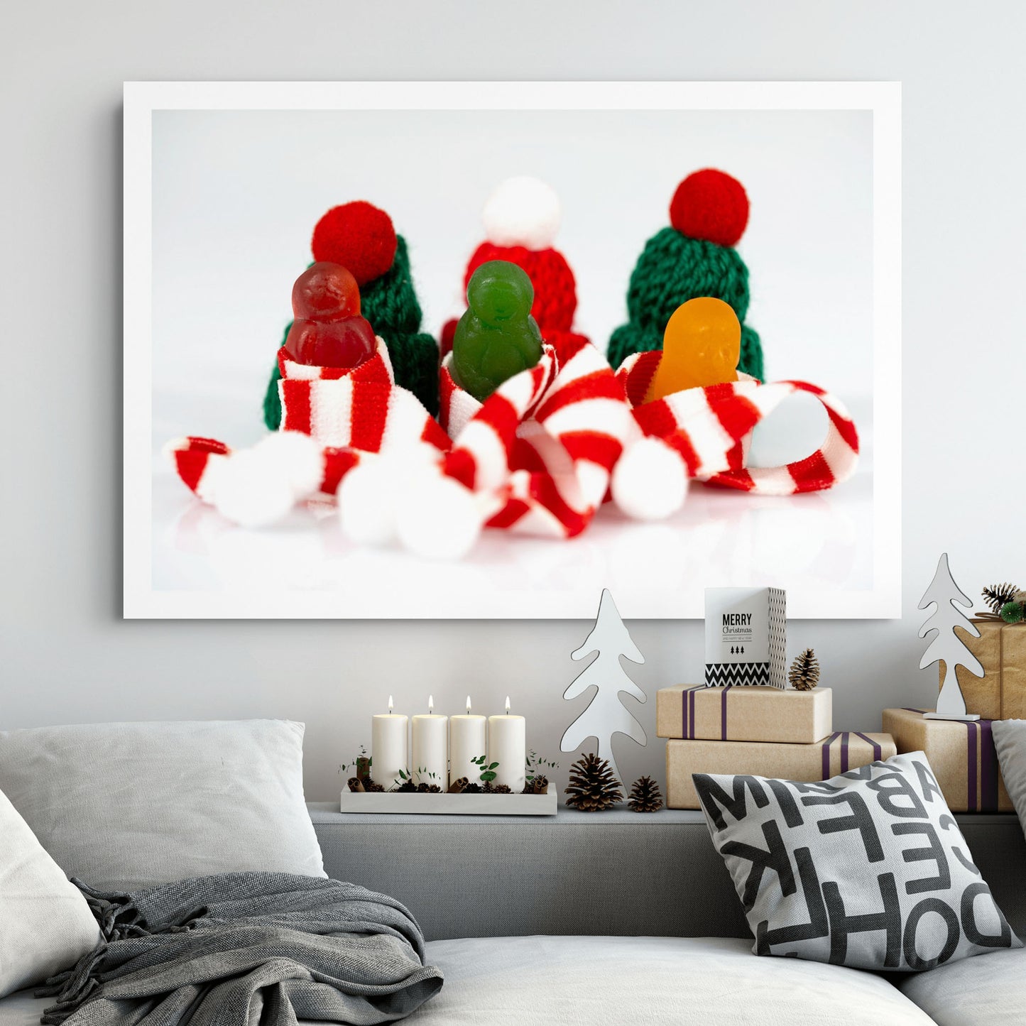 Santa Babies photographic artwork showing three colourful miniature figures among Christmas scarves and knitted hats displayed in a contemporary living room.