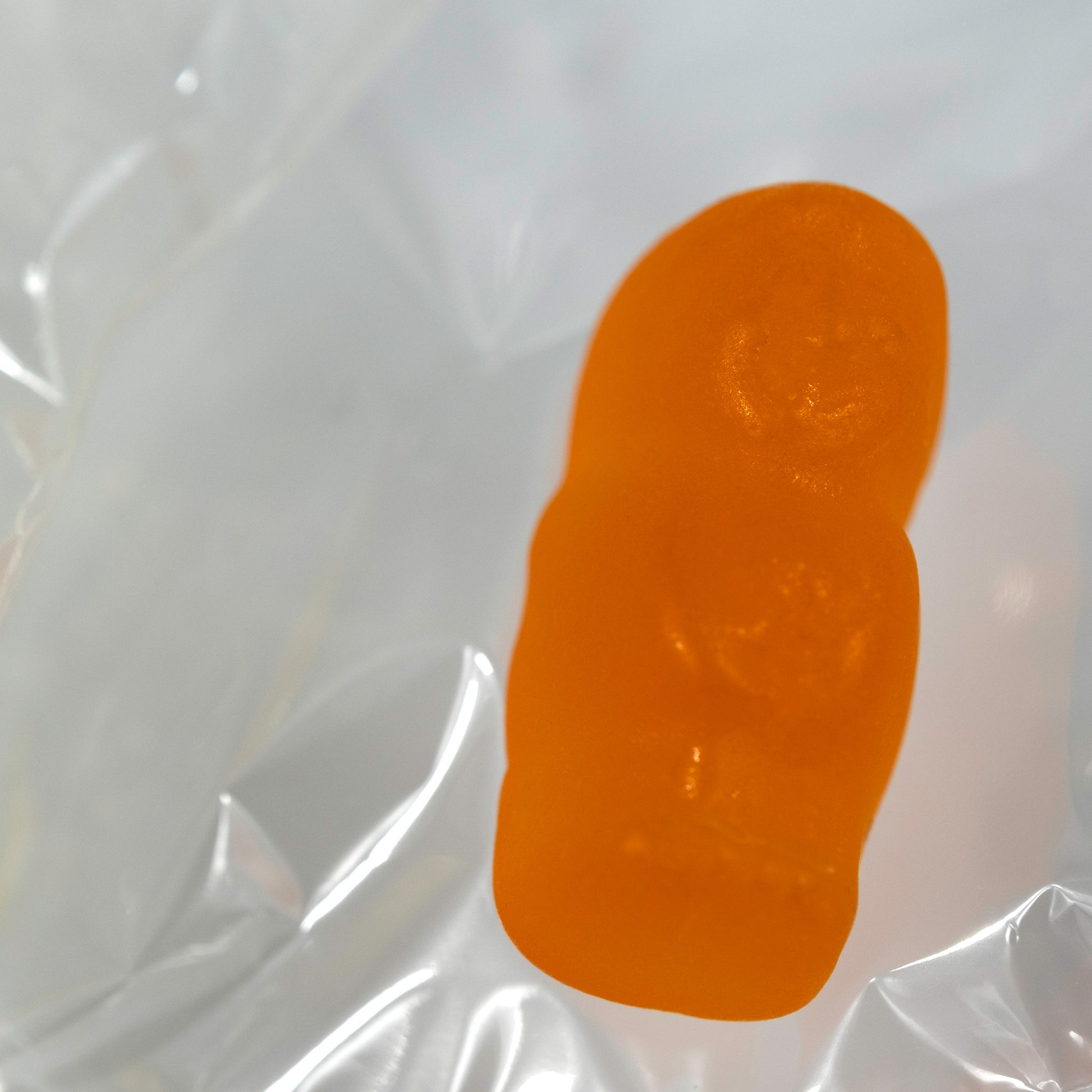 Close-up of an orange translucent baby-shaped figure surrounded by reflective folds of clear material.