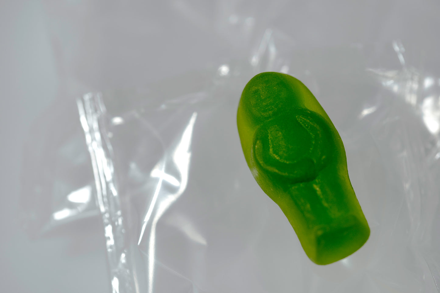 Green translucent baby-shaped figure floating within a pale field of folded transparent material.