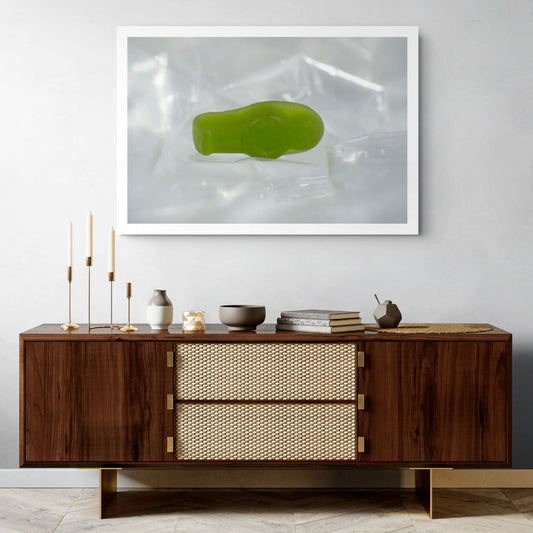 Sleep Like A Baby photographic artwork showing a small translucent green baby-shaped figure lying within pale transparent material in a contemporary interior.