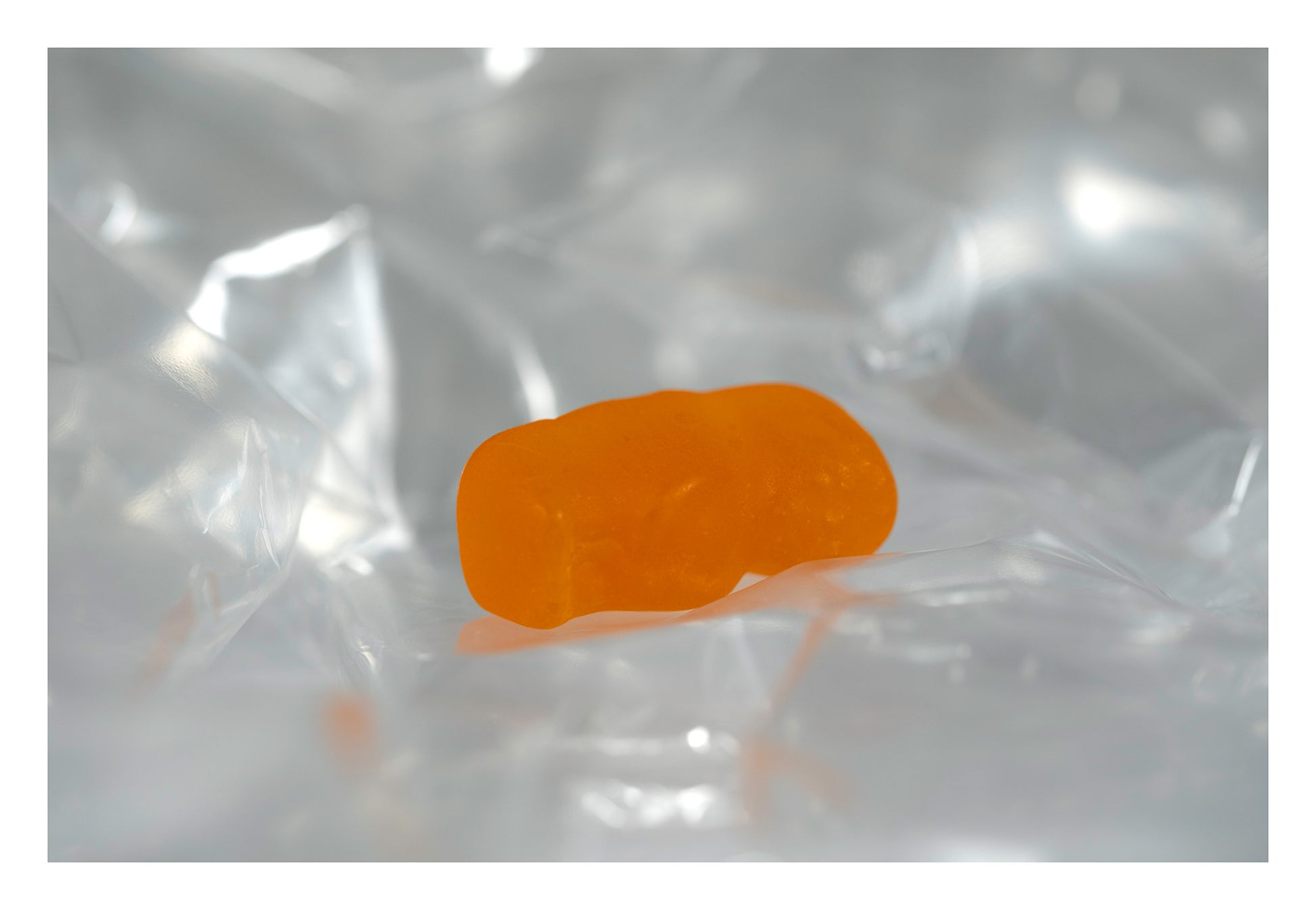 Translucent orange baby-shaped figure lying within a luminous landscape of folded clear material.